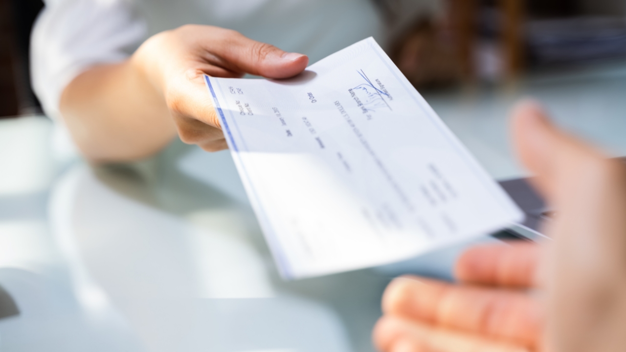 Hombre entregando cheque de salario adelantado a otra persona